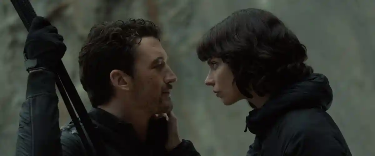 Two assassins embrace in the woods.