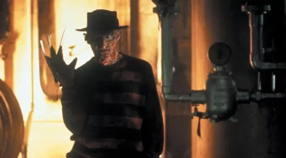 The villain, Freddy Krueger, stands in the dark.