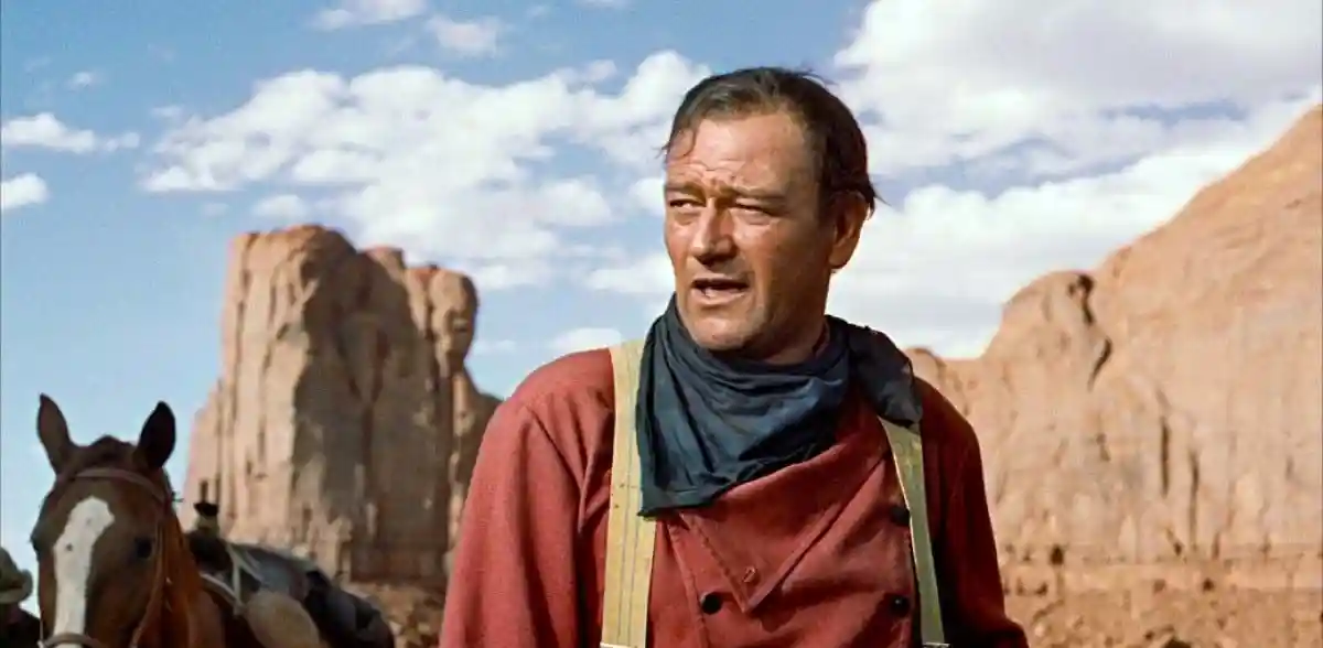John Wayne stands in front of a rock face in Mounment Valley.