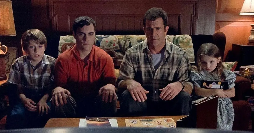 A family watches the television in awe of what they see.